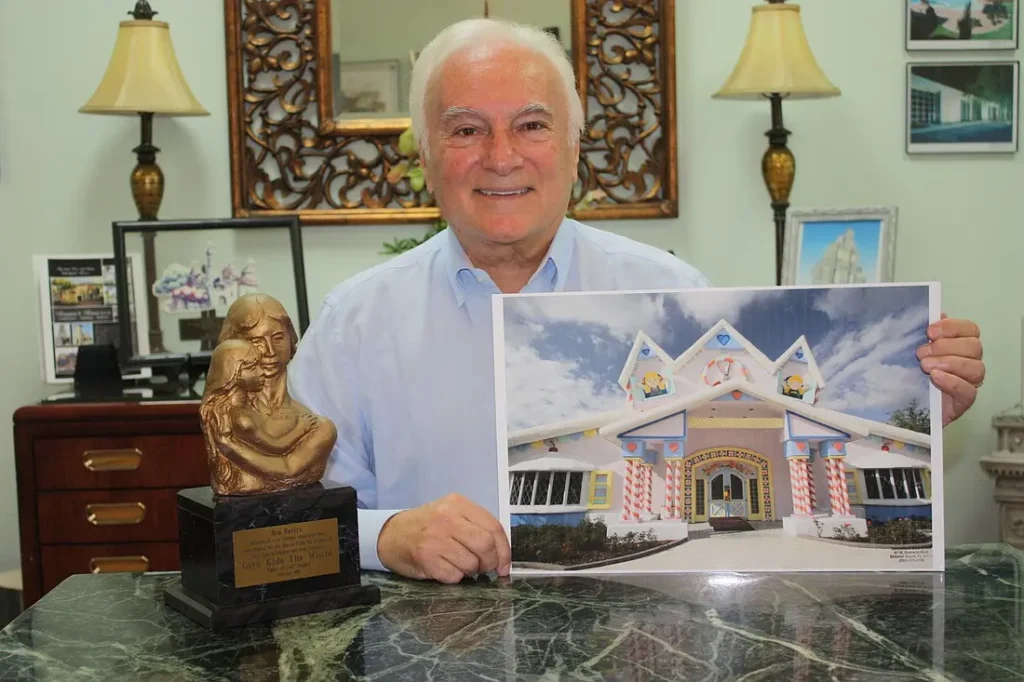 Ben in office holding Give Kids The World Village picture