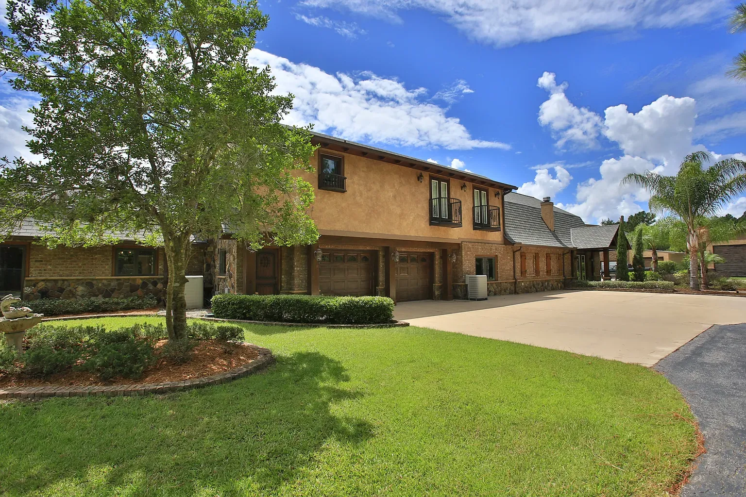 Magnificent home renovation reimagined by award-winning architect Benjamin P. Butera, where a sloped roof perfectly harmonizes with a home addition, a textured facade in a southwestern earthy palette, and new garage doors to create a rustic exterior.