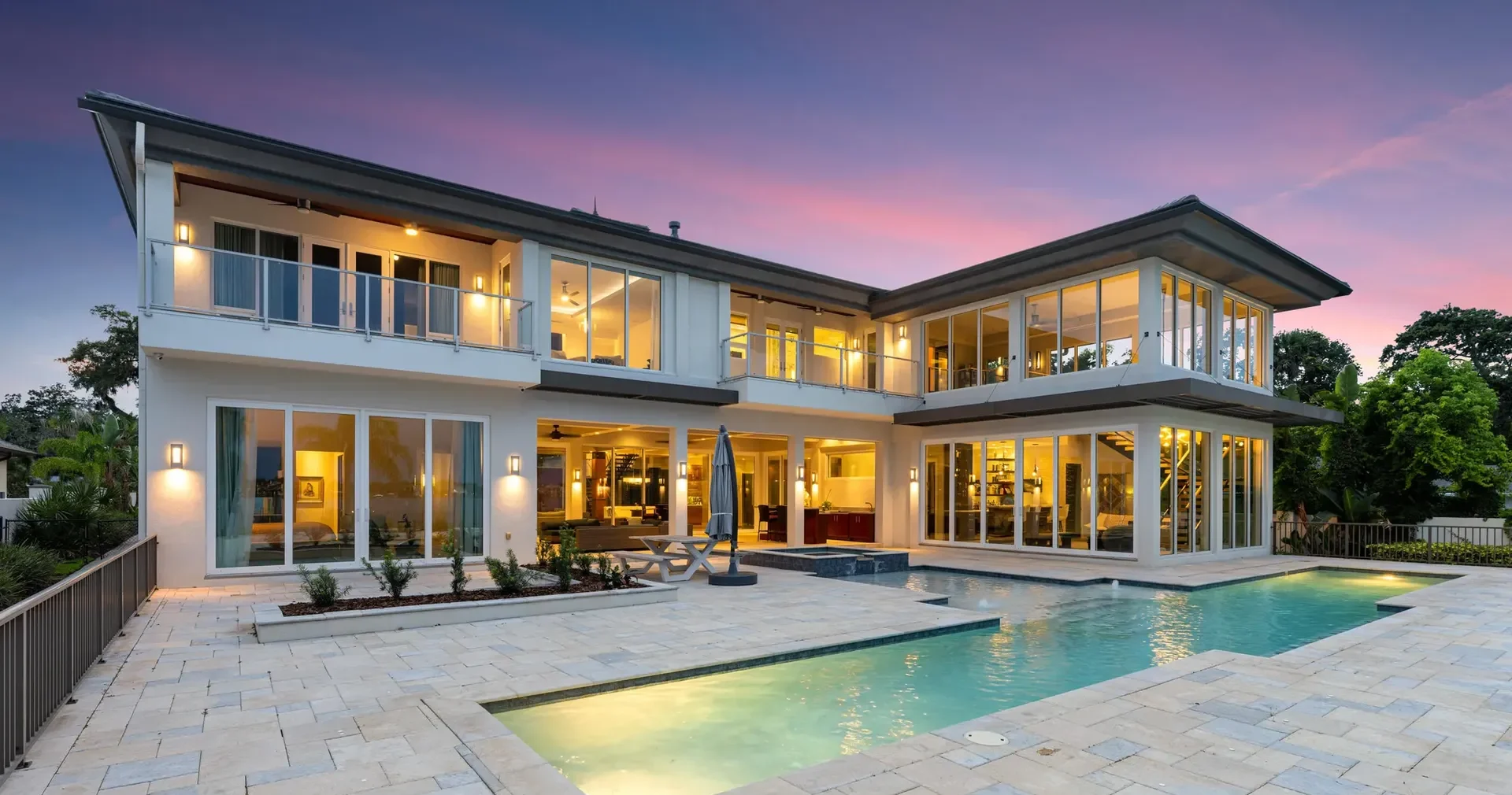 Two-story Butera Designs custom homes outdoor living residential house with wide glass windows, stone patio, pool and spa