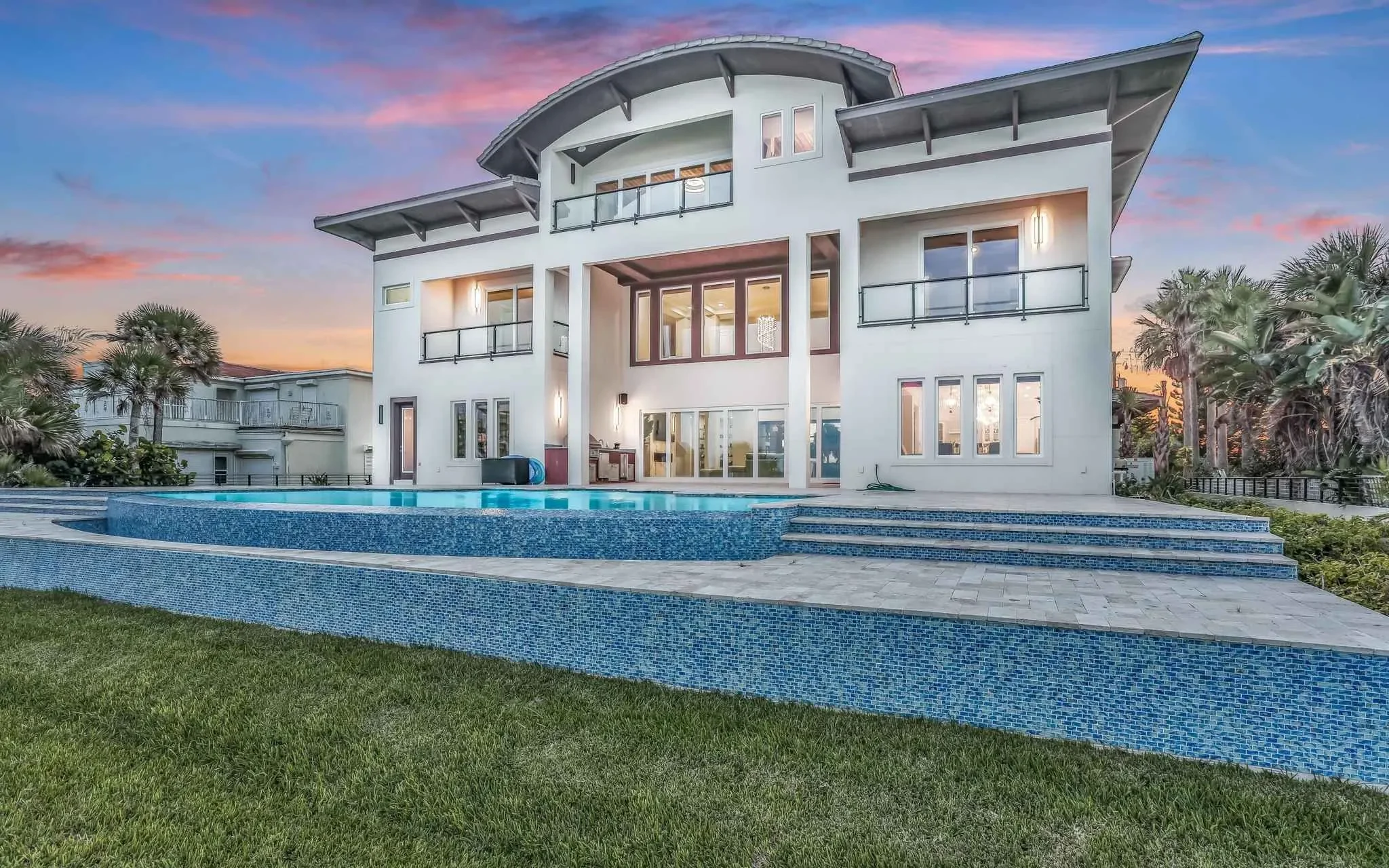 Modern home by Ben Butera luxury home architect with curved roof, balcony and glass doors for ocean views and outdoor living.
