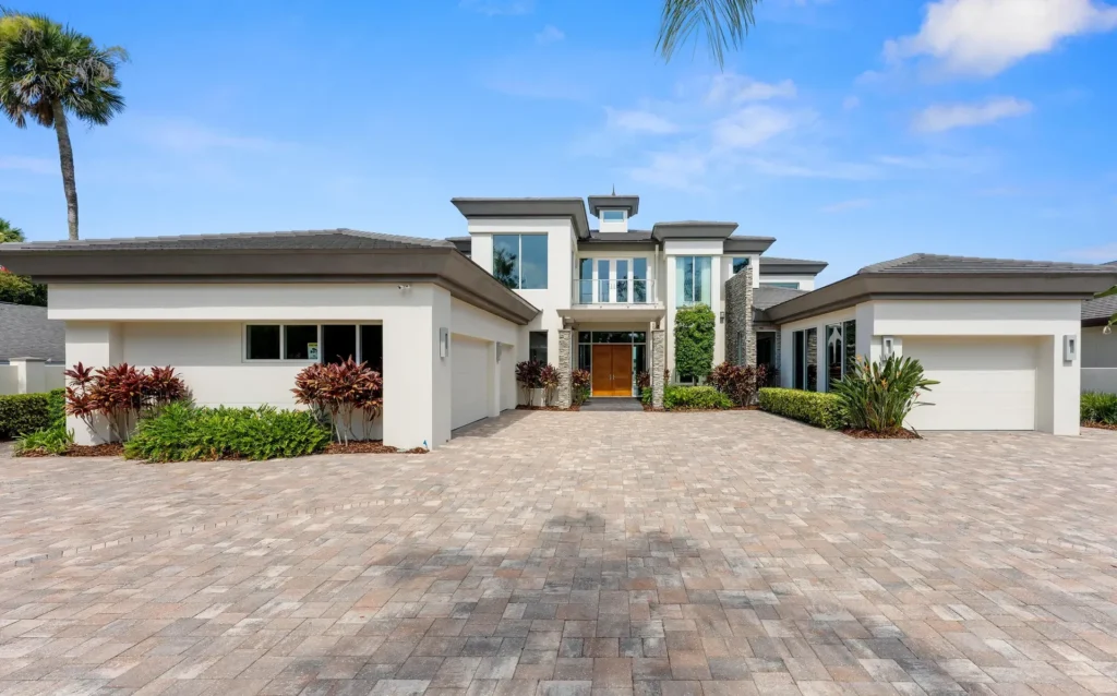 Waterfront property with brick driveway, portico and chic garden shows Luxury custom homes by top Florida architecture studio
