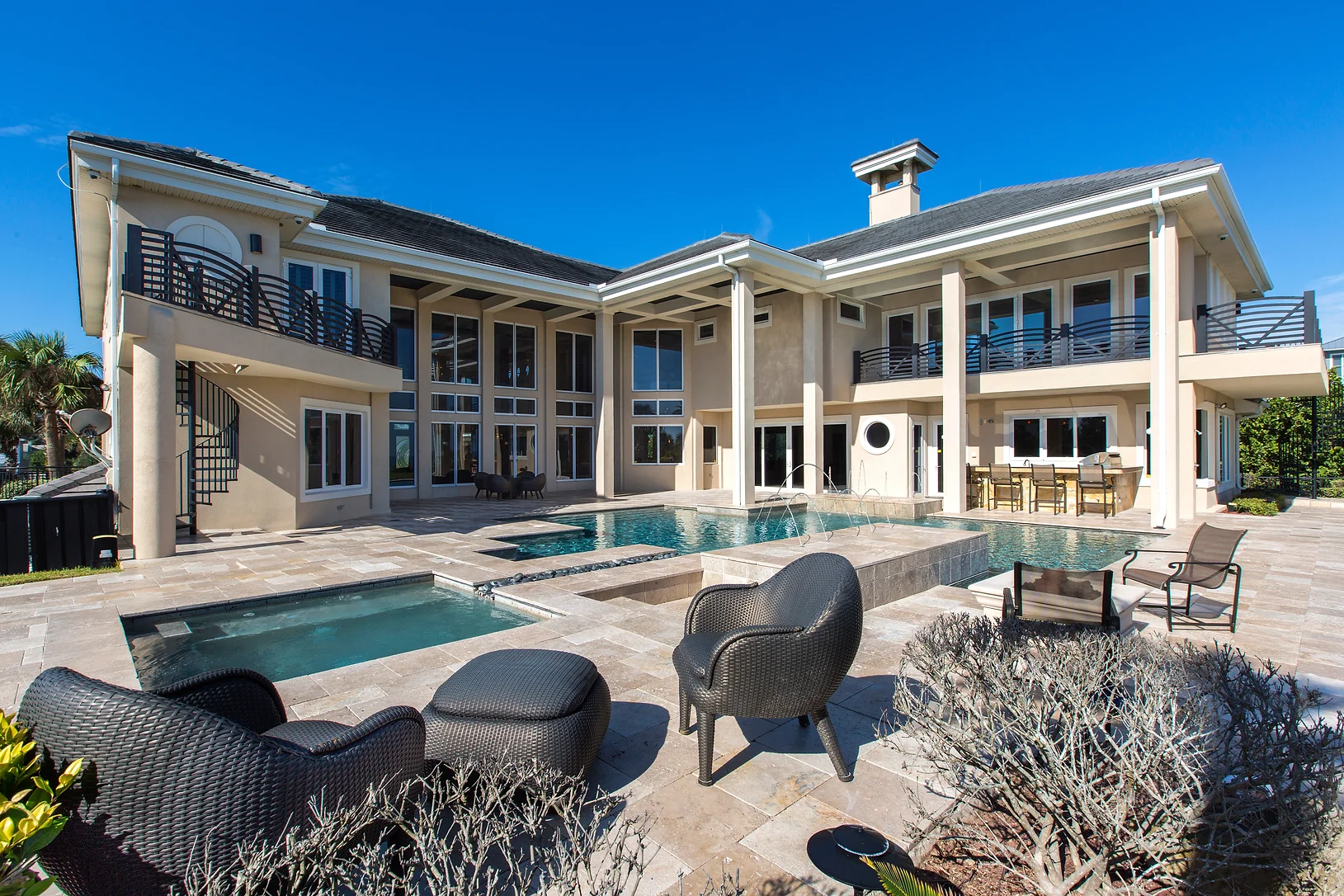 Back View of Eclectic Oceanfront House Oceanfront luxury custom home with large windows, balconies, swimming pool with water fountain and lounge area by Ben Butera.