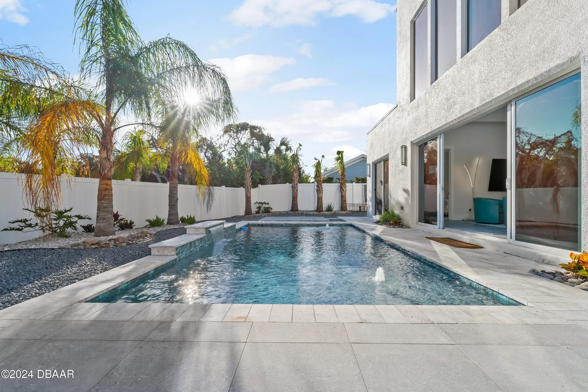 Outdoor living space with slider glass door, modern pool design and contemporary landscape architecture by Benjamin P. Butera