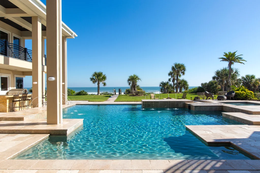 Yard of Eclectic Oceanfront Home Oceanfront poolside view of a Daytona Beach Shores custom luxury home with outdoor kitchen designed by architect Ben Butera.
